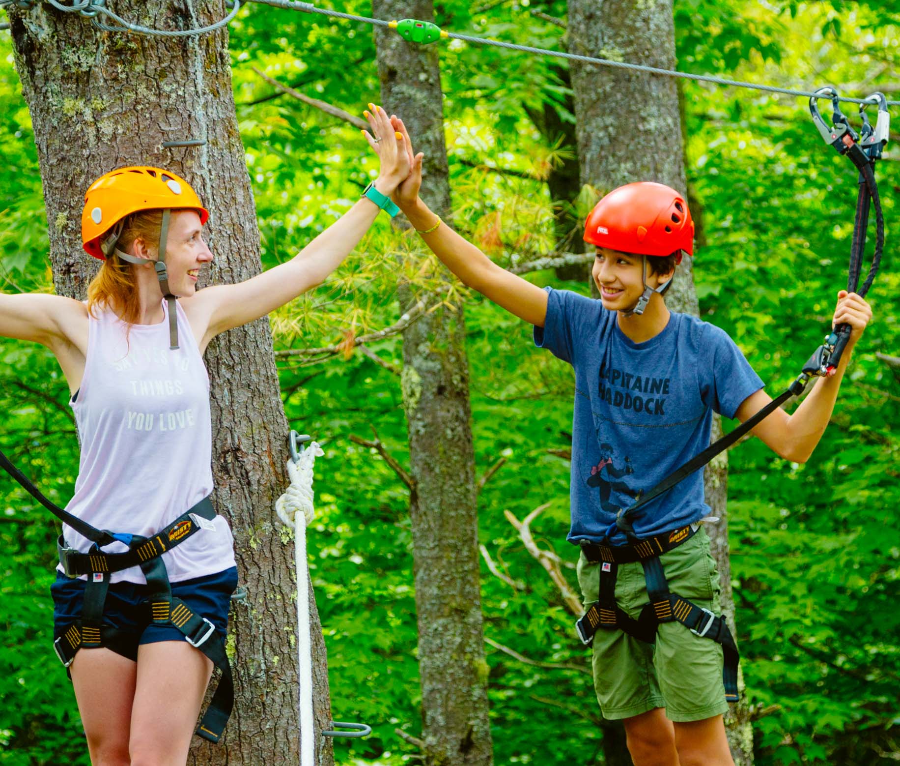 Two campers high fiving on the ropes course