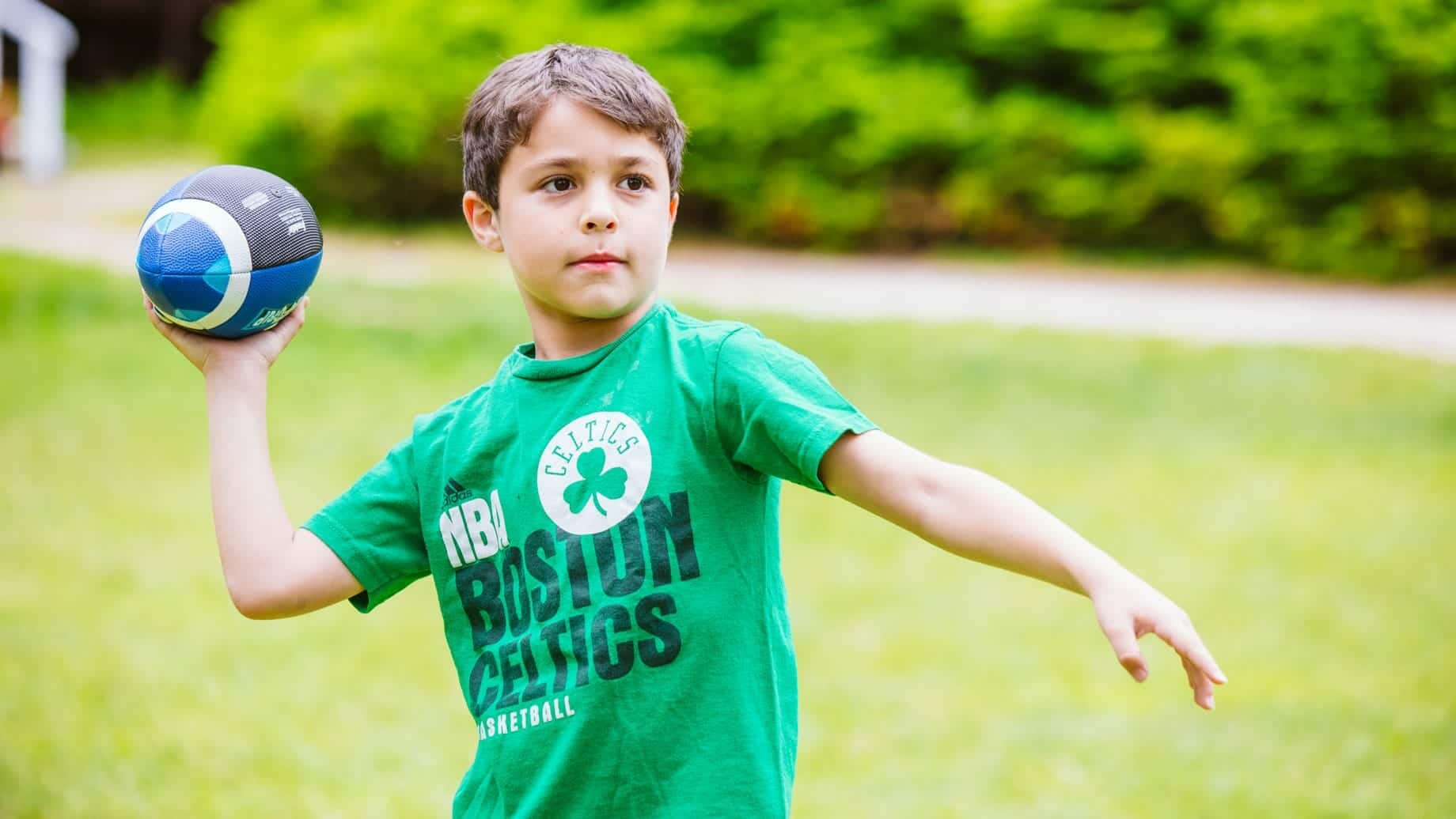 Young boy playing football at Camp Waziyatah