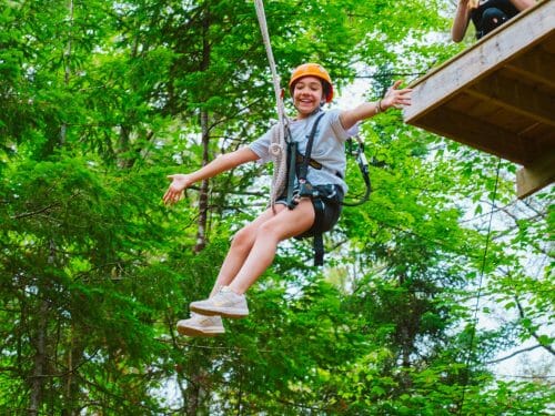 Girl zip lining with her arms stretched out