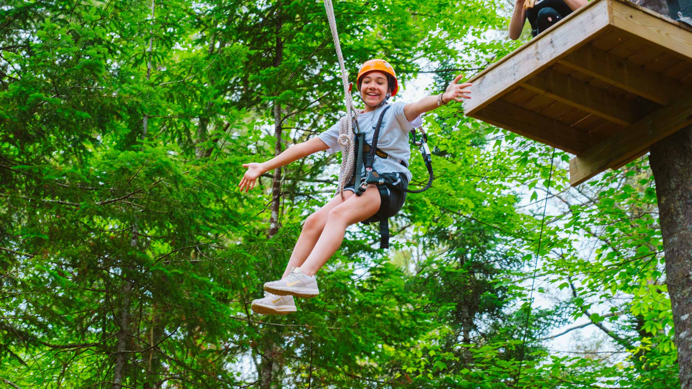 Girl zip lining with her arms stretched out